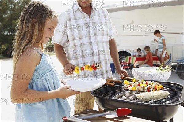 Man grilling dinner for family on beach. Date : 2008