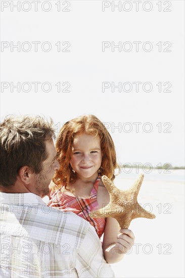 Father carrying daughter and starfish. Date : 2008