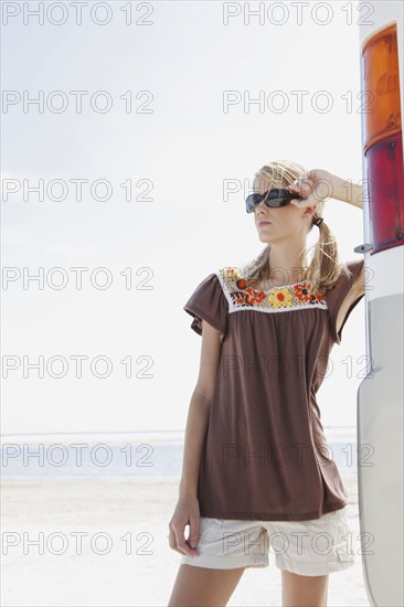 Young woman posing next to motor home on beach. Date : 2008