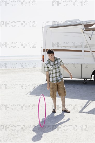 Young man spinning hula hoop on beach. Date : 2008