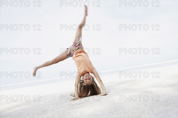 Girl doing cartwheel on beach. Date : 2008