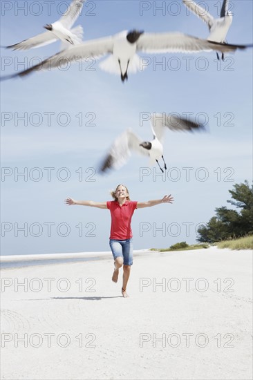 Girl chasing birds on beach. Date : 2008