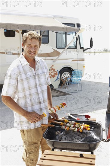 Man grilling shish kebabs on beach. Date : 2008