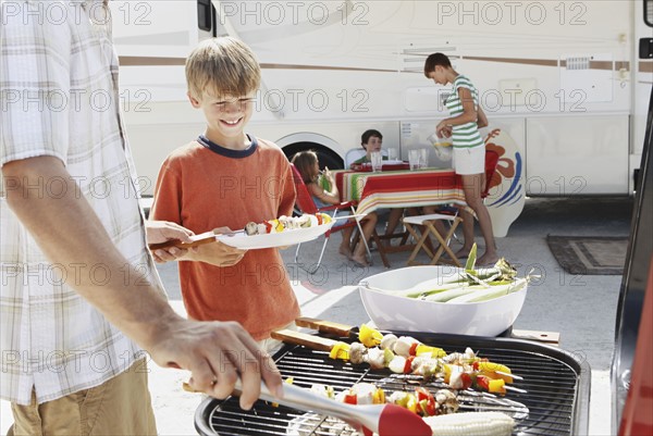 Man grilling dinner for family on beach. Date : 2008