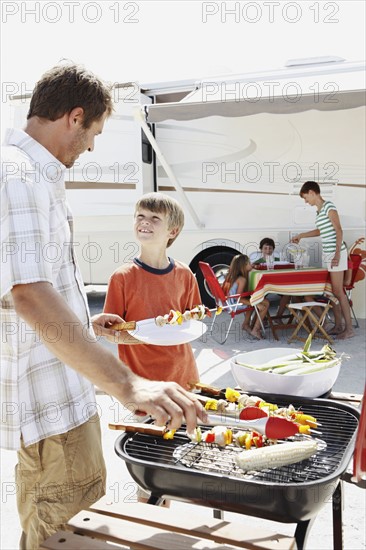 Man grilling dinner for family on beach. Date : 2008