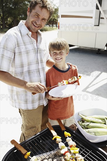 Man grilling dinner for family on beach. Date : 2008