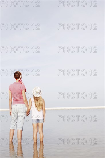 Mother and daughter holding hands on beach. Date : 2008