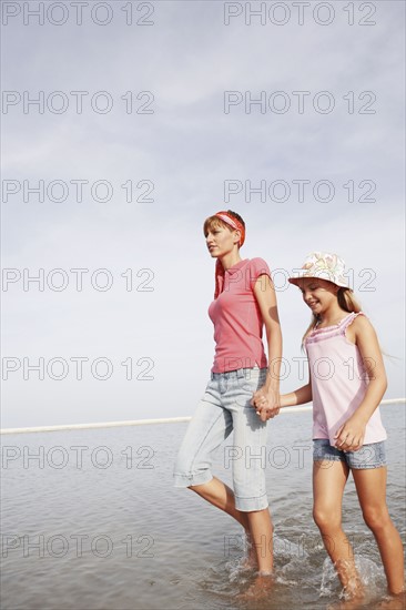 Mother and daughter walking in ocean. Date : 2008