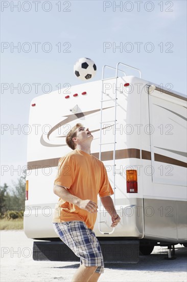Young man playing with soccer ball on beach. Date : 2008
