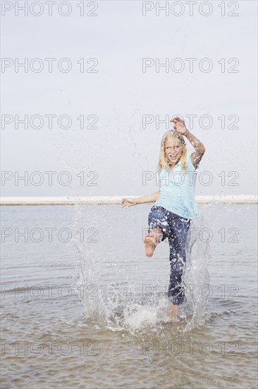 Girl kicking water at beach. Date : 2008