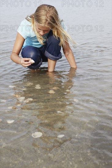 Girl looking for shells in shallow water. Date : 2008