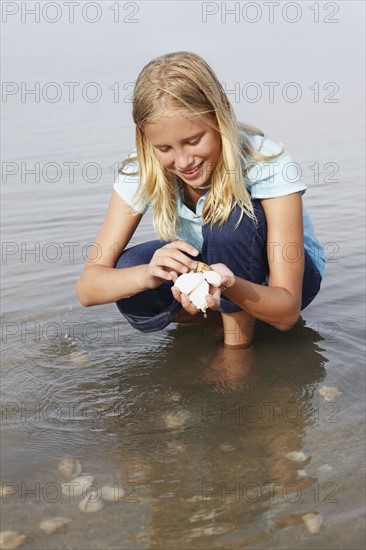 Girl looking for shells in shallow water. Date : 2008