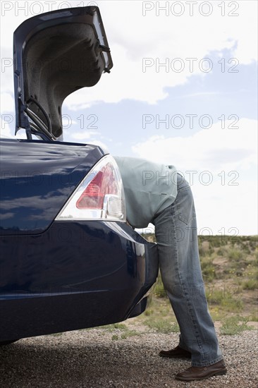 Man looking in trunk of car. Date : 2008