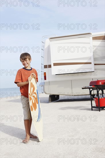 Boy holding skimboard on beach. Date : 2008