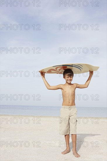 Boy holding skimboard on beach. Date : 2008