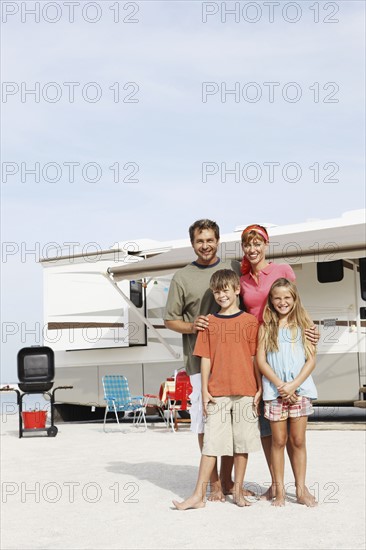 Family posing by motor home on beach. Date : 2008