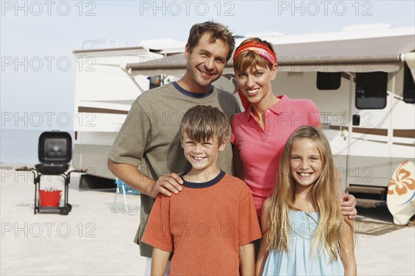 Family posing by motor home on beach. Date : 2008