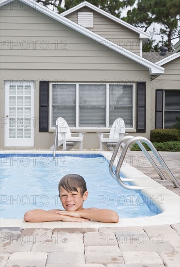 Boy leaning on edge of swimming pool. Date : 2008