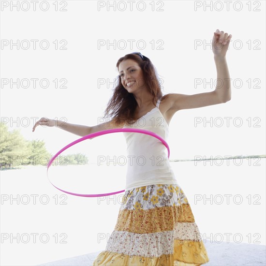 Young woman hula hooping on beach. Date : 2008