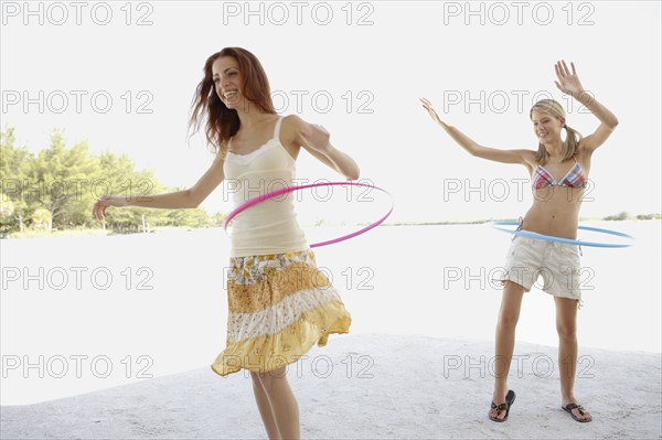 Young women hula hooping on beach. Date : 2008