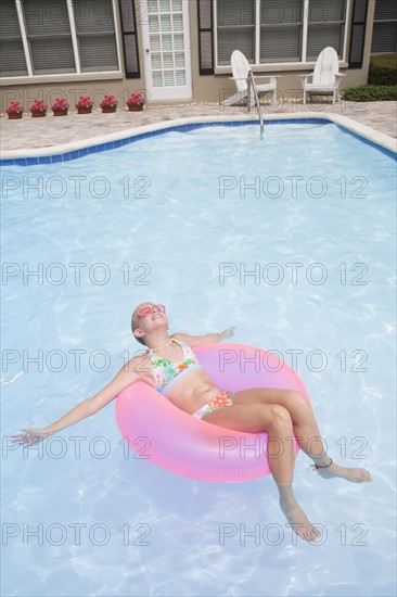 Girl relaxing on inflatable ring in swimming pool. Date : 2008