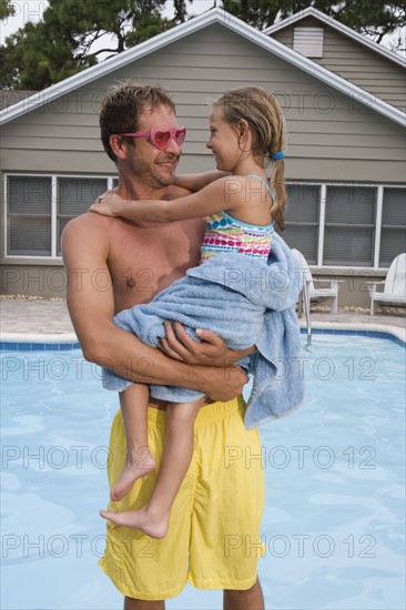 Father holding daughter by swimming pool. Date : 2008