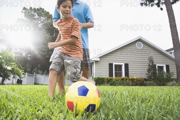 Father and son playing soccer in backyard. Date : 2008