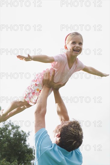 Father lifting daughter in backyard. Date : 2008