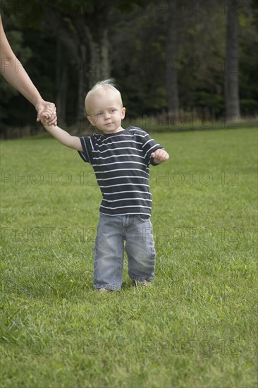 Baby boy walking in park with parent. Date : 2008