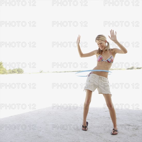Young woman hula hooping on beach. Date : 2008