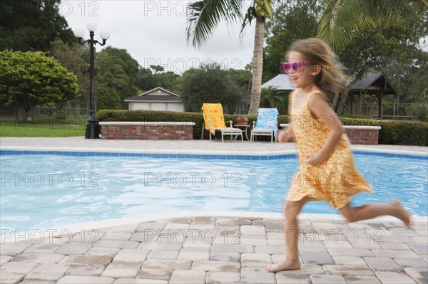 Girl running beside swimming pool. Date : 2008