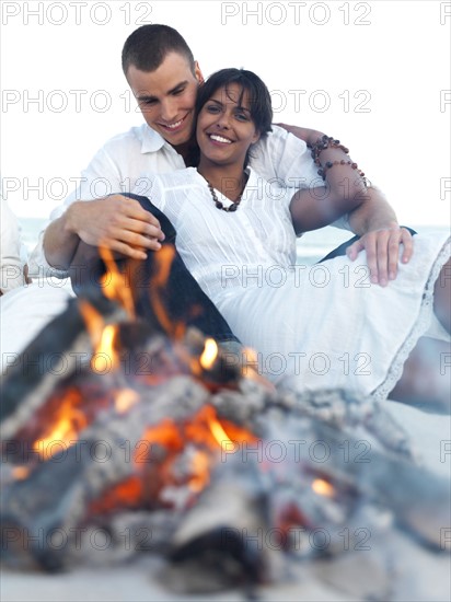 Young couple hugging by campfire on beach. Date : 2008