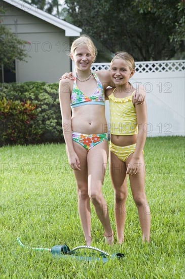 Girls playing with sprinkler in backyard. Date : 2008