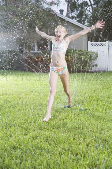 Girl running through sprinklers. Date : 2008