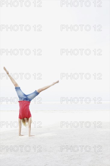 Girl doing cartwheel on beach. Date : 2008