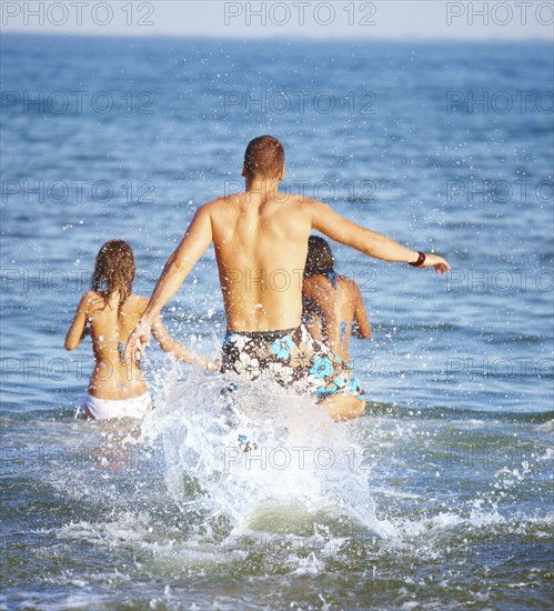 Young friends running into ocean. Date : 2008