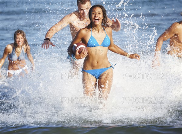 Young friends playing football in ocean. Date : 2008