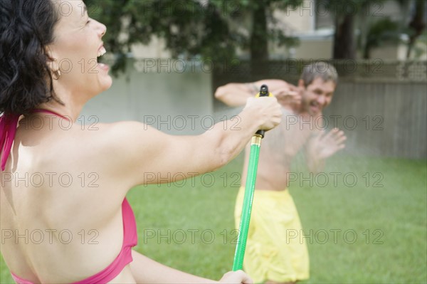 Woman spraying man with hose in backyard. Date : 2008