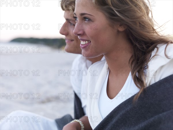 Young couple wrapped in blankets on beach. Date : 2008