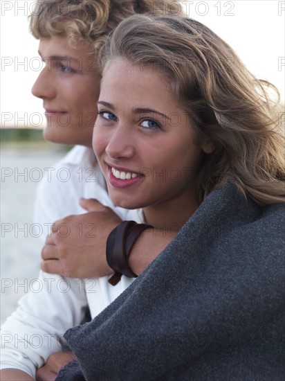 Young couple wrapped in blankets on beach. Date : 2008