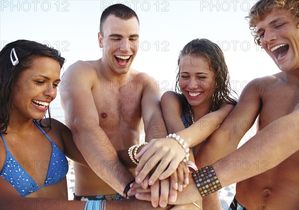 Young couples stacking hands on beach. Date : 2008