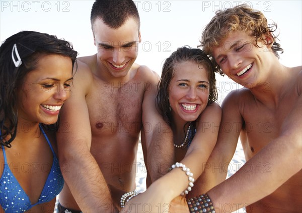 Young couples stacking hands on beach. Date : 2008