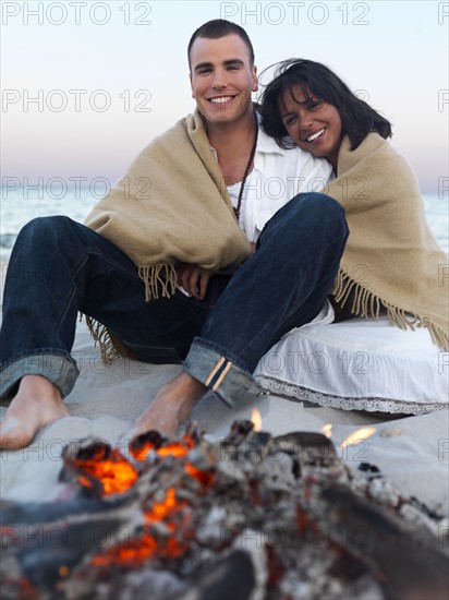 Young couple relaxing by campfire on beach. Date : 2008