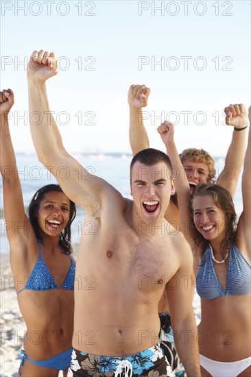 Young friends raising arms on beach. Date : 2008