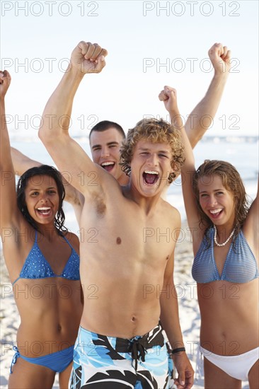 Young friends raising arms on beach. Date : 2008