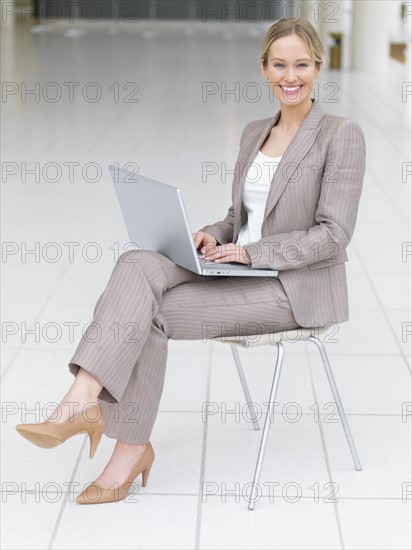 Businesswoman working on laptop in office lobby. Date : 2008