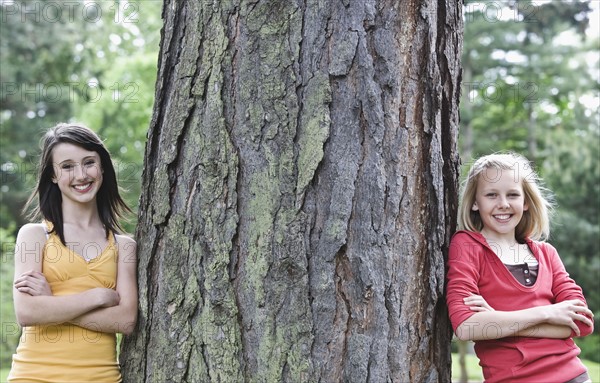 Girls leaning against large tree. Date : 2008