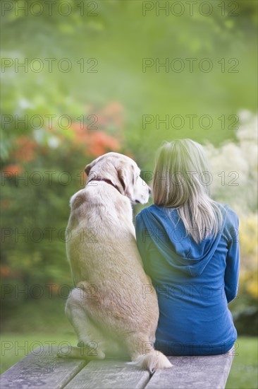 Girl and dog sitting together on picnic table. Date : 2008