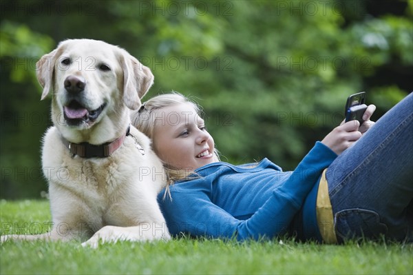 Girl resting on dog in park. Date : 2008