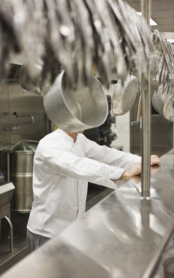 Chef leaning on shelf in commercial kitchen. Date : 2008